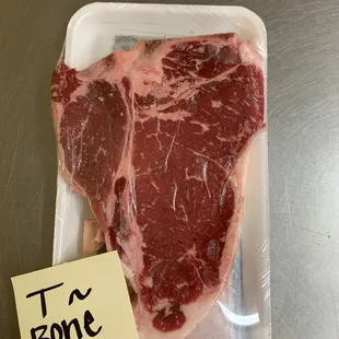 a piece of beef on a tray with a note that says t bone