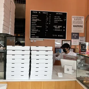 a woman behind a counter in a pizza shop