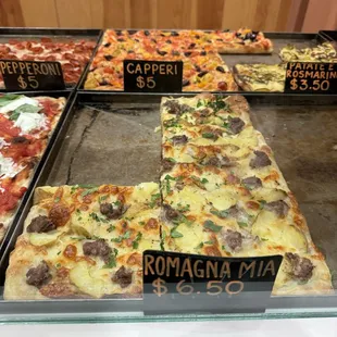 a variety of pizzas in a display case