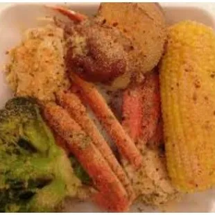 crab legs, corn, broccoli, and potatoes in a styrofoam container