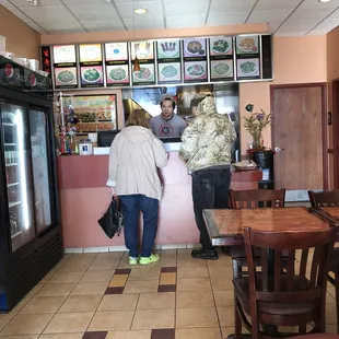 a couple of people standing at a counter in a restaurant