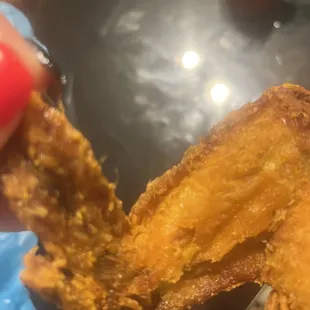 a hand holding a fried chicken