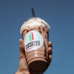 a hand holding a cup of espresso