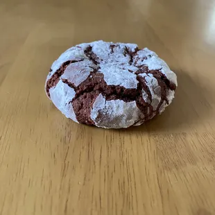 a chocolate crinkle cookie on a wooden table