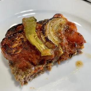 a piece of meat with pickles on it