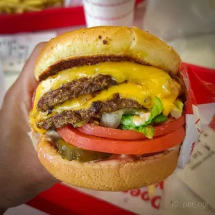 ows a hand holding a cheeseburger