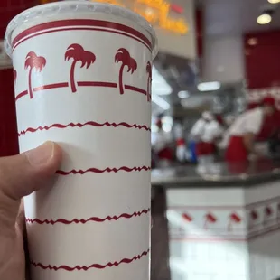 ows a hand holding a paper cup