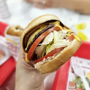 ows a hand holding a hamburger