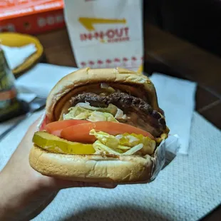 ows a hand holding a hamburger