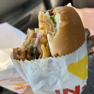 ows a hand holding a sandwich