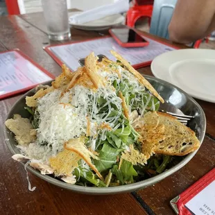 a plate of salad with cheese and parmesan chips