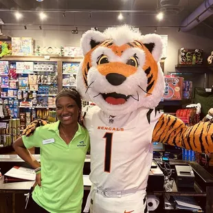 a woman standing next to a tiger mascot