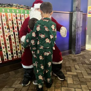 a boy in pajamas hugging santa claus