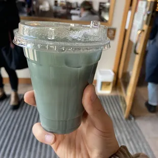 a hand holding a green drink