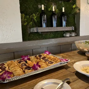 a wooden table with plates of food and wine bottles