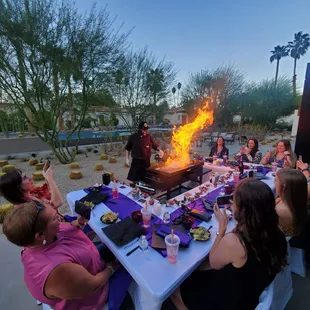 a group of people sitting around a table with food on it