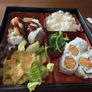 a tray of sushi with rice, lettuce, meat, and