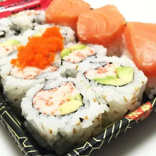 a tray of sushi with salmon, avocado, and cavia