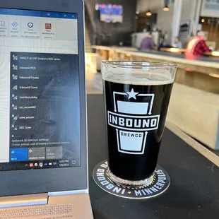a pint of beer next to a laptop