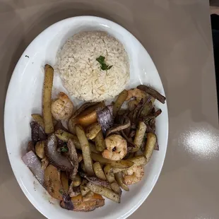 Lomo mixto (chicken, shrimp, steak) with sautéed onions, tomatoes and fries, served with a side of rice.