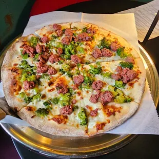 a pizza with meat and broccoli