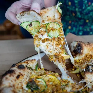 a person taking a slice of pizza