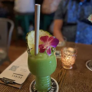 a green drink with a purple flower