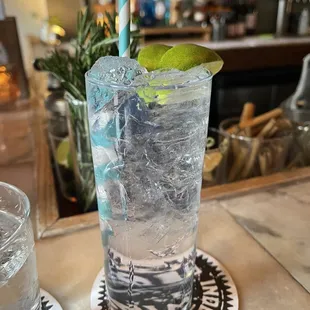 a tall glass of water with a lime garnish