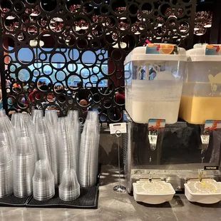 a beverage dispenser and cups on a counter