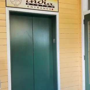 two green doors in a yellow building