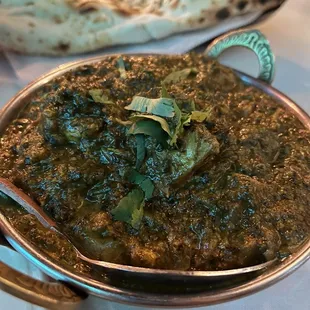 a bowl of spinach and a plate of naan bread