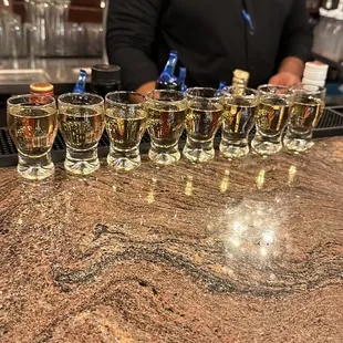 a man standing behind a bar filled with shot glasses