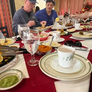 a group of people sitting at a table with plates of food