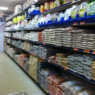 Wall of mostly dried staples: beans, grains, flours.