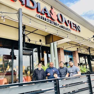 three men standing in front of the restaurant