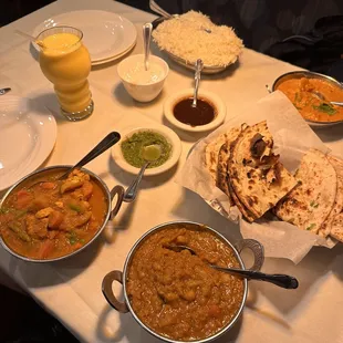 Counter clockwise: Mango Lassi, Chicken Vegetable Curry, Chana Masala, Roti, Garlic Naan, Chicken Tikka Masala, Basmati Rice, and Raita.