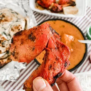 a hand holding a skewer of chicken