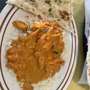 a plate of chicken curry and rice with naan bread