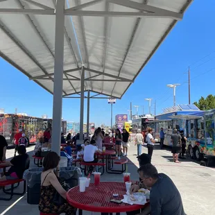 a group of people sitting at tables under a canopy