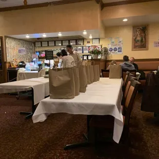 Assembly line of paper bags for orders to go in the center of the restaurant mostly for food delivery services.