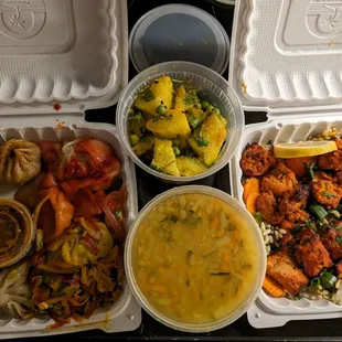 Takeout order including momos, lentil soup, potato dish, chicken dish