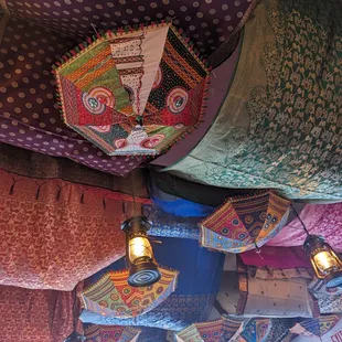 Ceiling is filled with brightly covered saris and parasols.