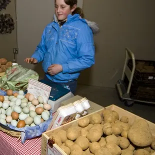a woman standing in front of a table full of produce