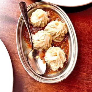 a bowl of dumplings and a spoon on a table
