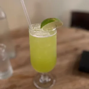 a glass of limeade with a straw and a lime slice