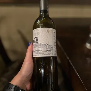 a hand holding a bottle of wine
