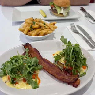 eggs benedict with my choice of bacon, truffle fries and wagyu burger in the back