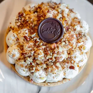 Our Banofee Tart features banana &amp; dulce de leche flavors topped with Chantilly cream, pecans, &amp;  an Indulge chocolate coin.