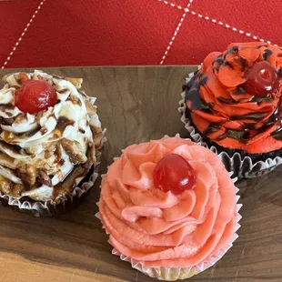 three cupcakes on a wooden board