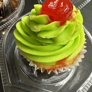 a cupcake with green frosting and a cherry on top